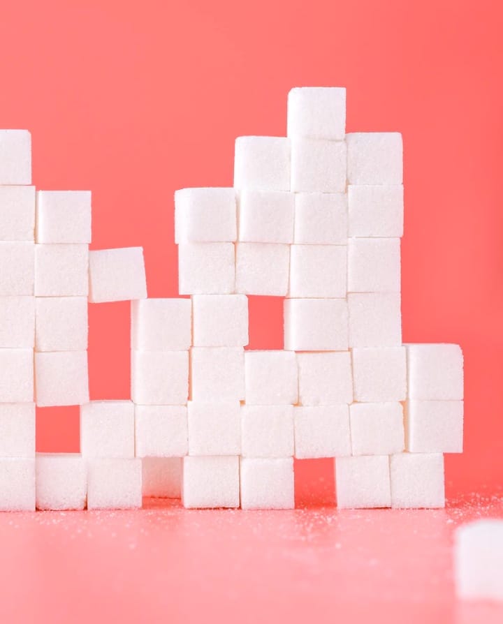 A lot of sugar cubes stacked on top of each other on a palette red background